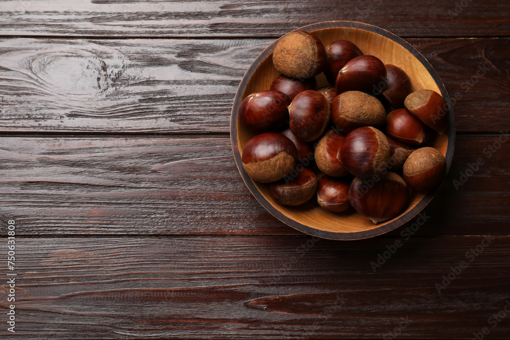 Sweet fresh edible chestnuts in bowl on wooden table, top view. Space for text Sweet fresh edible chestnuts in bowl on wooden table, top view. Space for text