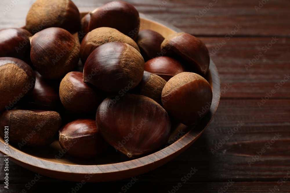 Sweet fresh edible chestnuts in bowl on wooden table, closeup Sweet fresh edible chestnuts in bowl on wooden table, closeup