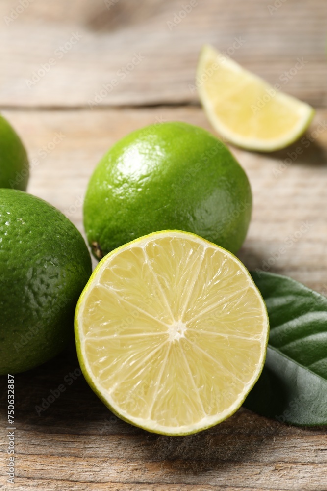 Whole and cut fresh limes on wooden table, closeup Whole and cut fresh limes on wooden table, closeup