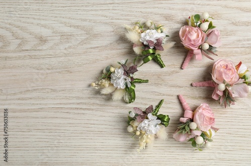 Stylish boutonnieres on white wooden table, flat lay. Space for text