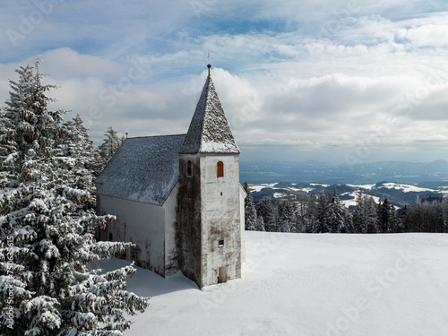 Church on top of the hill in winter next to ski resort. With beautiful landscape view on cloudy day photo