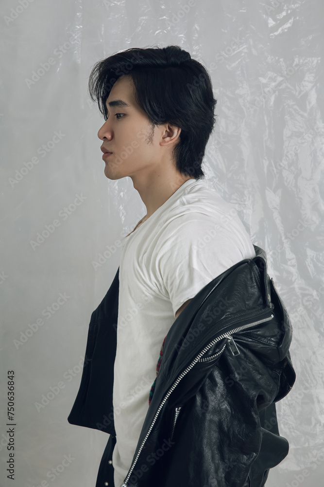 A stylish young Asian man standing in profile, showcasing a timeless fashion with a casual white t-shirt paired with a classic black leather jacket. His thoughtful expression, the elegant. A stylish young Asian man standing in profile, showcasing a timeless fashion with a casual white t-shirt paired with a classic black leather jacket. His thoughtful expression, the elegant.