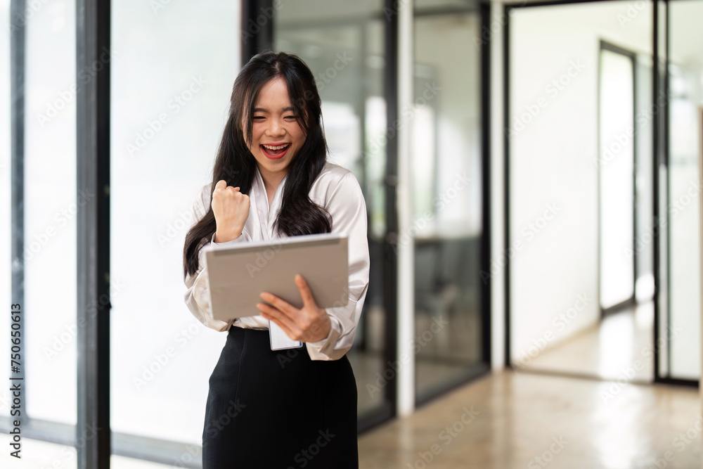 Attractive young asian business woman using digital tablet celebrate success or happy pose Attractive young asian business woman using digital tablet celebrate success or happy pose