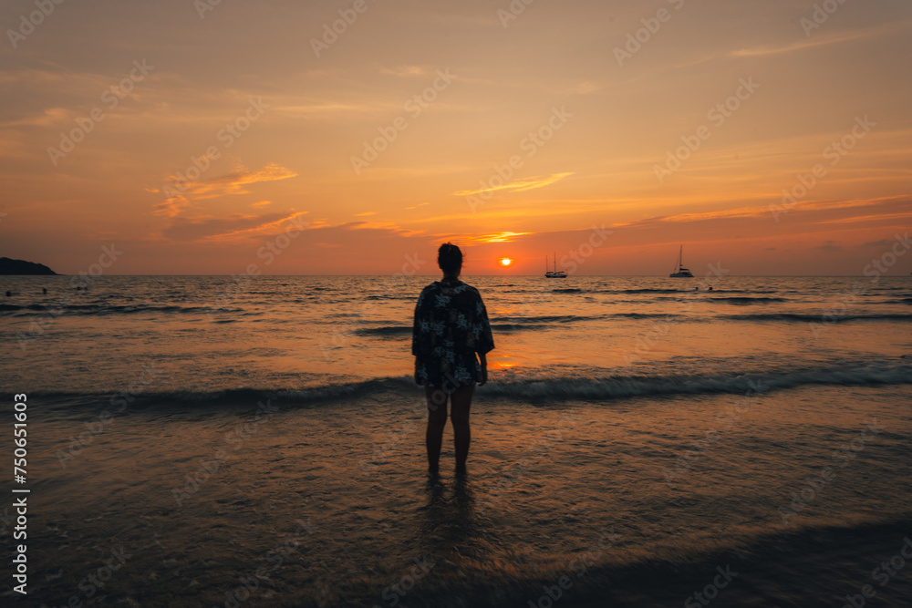 Obraz premium Summer sunset,Woman walking on the beach watching the sunset