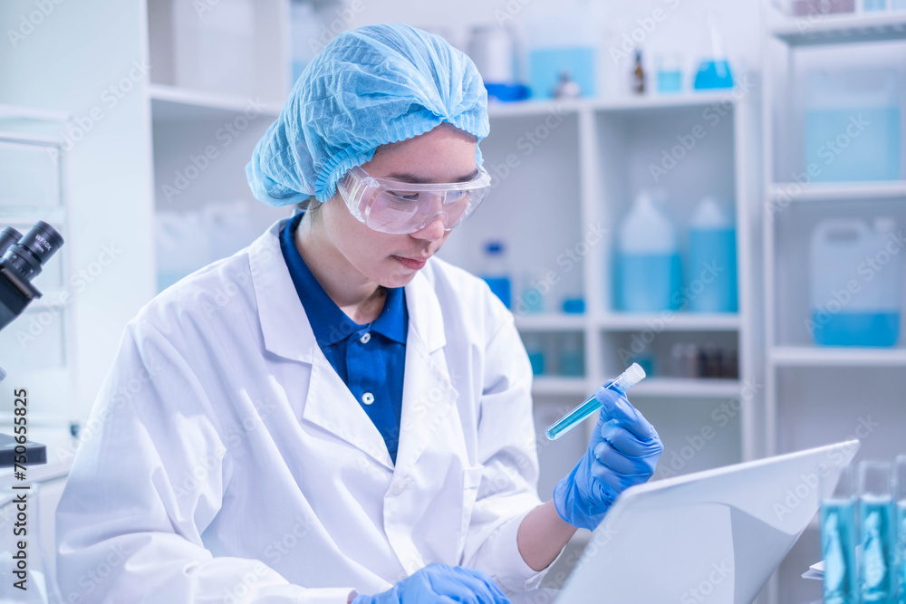 Closeup female woman scientist's hand holding blue liquid chemical chemistry test tube working in analyze science laboratory research experiment