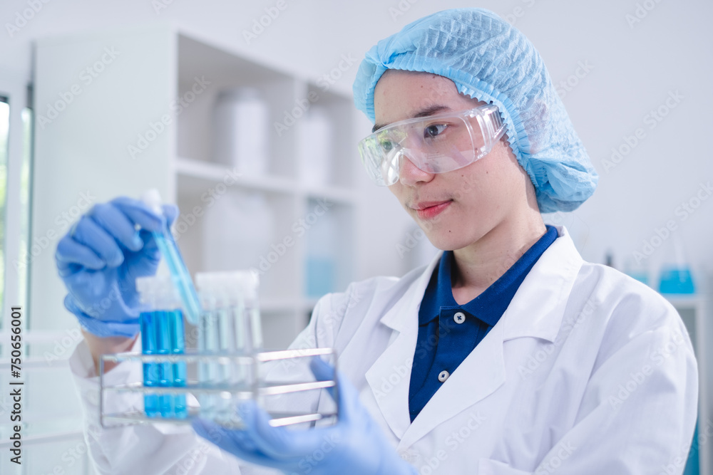 Closeup female woman scientist's hand holding blue liquid chemical chemistry test tube working in analyze science laboratory research experiment Closeup female woman scientist's hand holding blue liquid chemical chemistry test tube working in analyze science laboratory research experiment