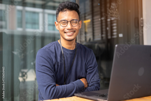 close up adult indian programmer man arm crossed while looking with confident smile at indoor office workplace for business startup and technology concept
