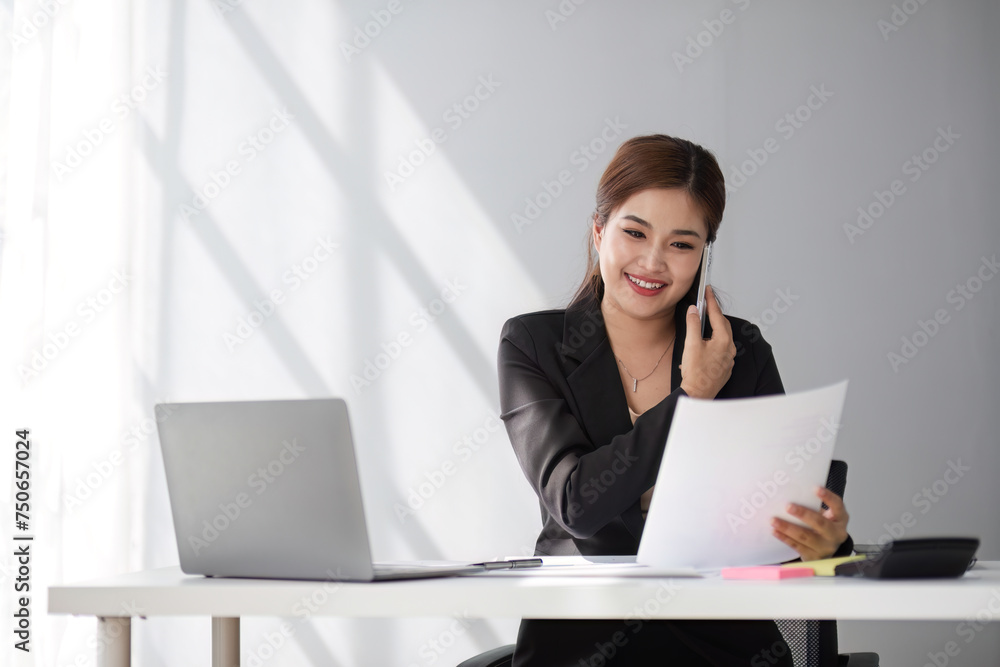 Businesswoman using laptop and mobile phone talking about work and managing company business Businesswoman using laptop and mobile phone talking about work and managing company business