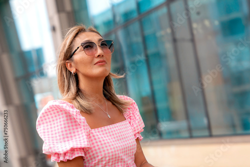 Asian matire woman in a pink dress and sunglasses with an pink umbrella walking,  sitting, having a fun time in the center of the city photo