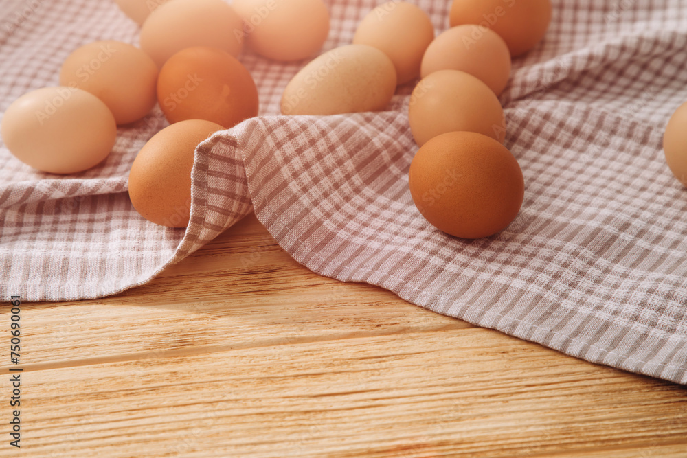 Chicken eggs of different brown and beige shades on a wooden background on grey kitchen towel. Easter background. Top view Chicken eggs of different brown and beige shades on a wooden background on grey kitchen towel. Easter background. Top view