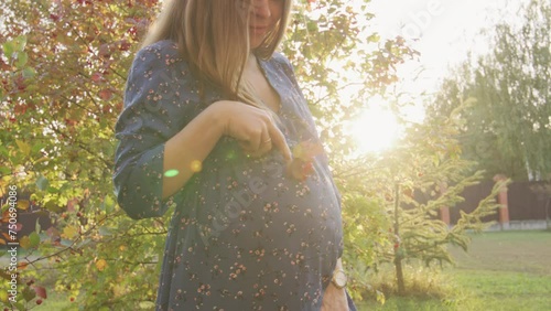 Beautiful pregnant woman having walk in the park photo