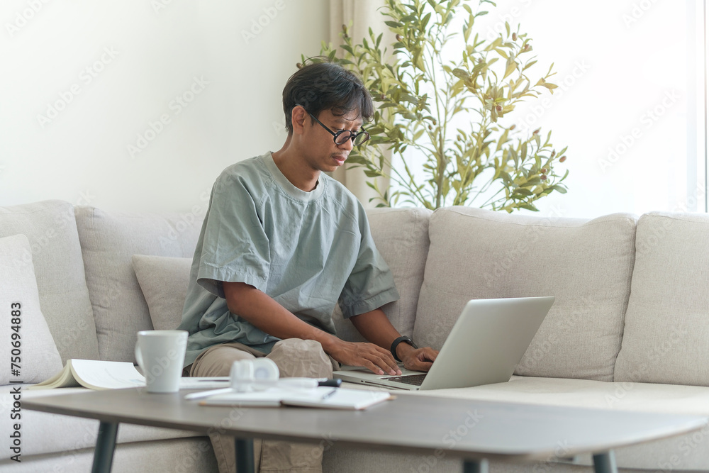 Handsome millennial man relaxing on couch and surfing internet on laptop. Handsome millennial man relaxing on couch and surfing internet on laptop.