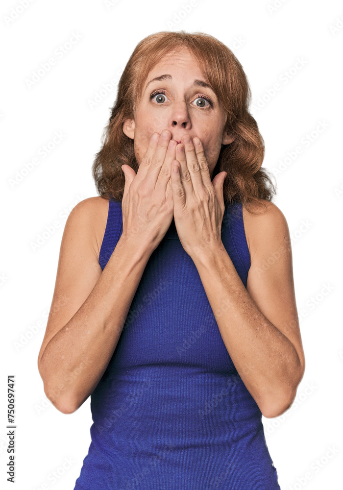 Redhead mid-aged Caucasian woman in studio shocked, covering mouth with hands, anxious to discover something new. Redhead mid-aged Caucasian woman in studio shocked, covering mouth with hands, anxious to discover something new.