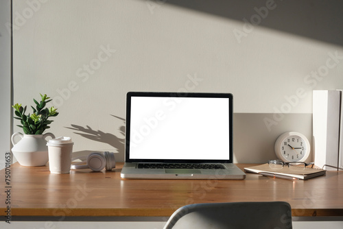 Front view laptop computer with blank display, potted plant and stationery on wooden table.