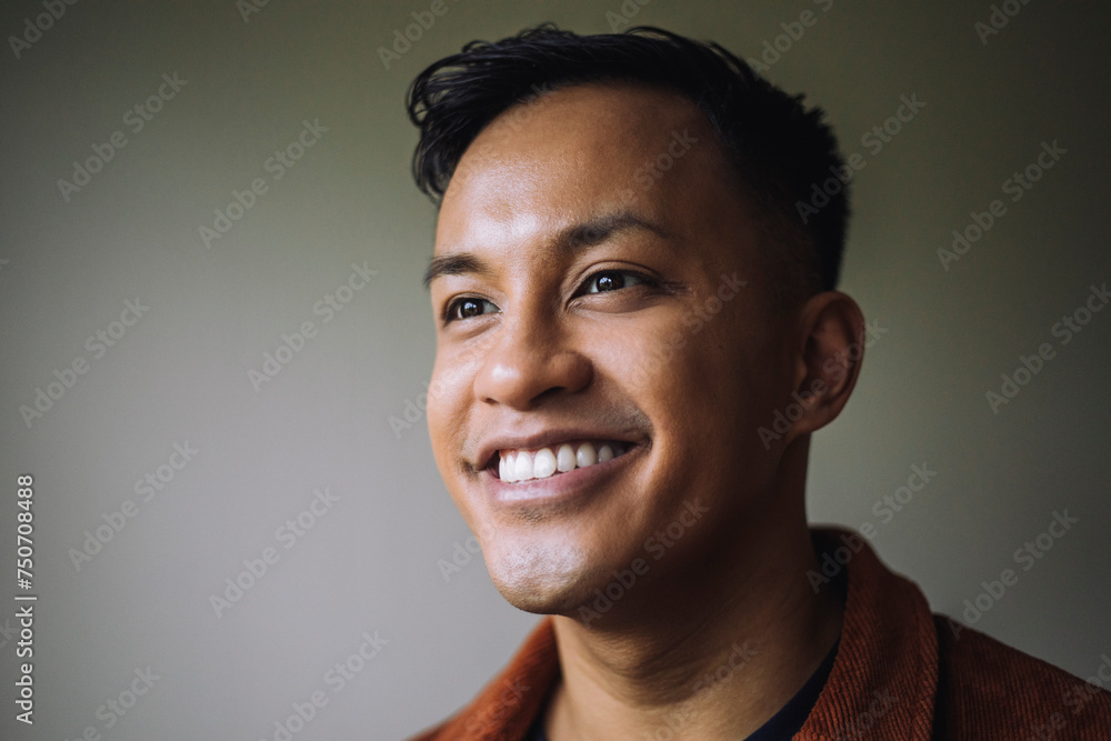 Smiling man looking away in front of wall at home Smiling man looking away in front of wall at home