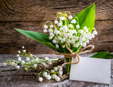 Blank greeting card with spring Lily of the valley flowers on rustic wooden brown background