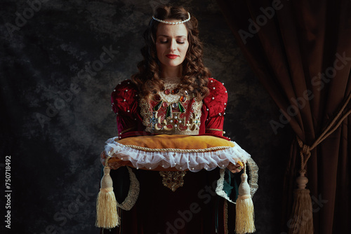 medieval queen in red dress with crown on pillow