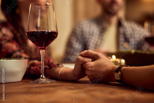 Close-up photo of people holding hands and praying before dinner.