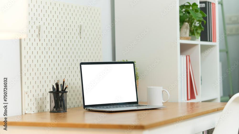 Home office desk with computer laptop, coffee cup and houseplant on wood table.