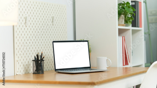 Home office desk with computer laptop, coffee cup and houseplant on wood table.