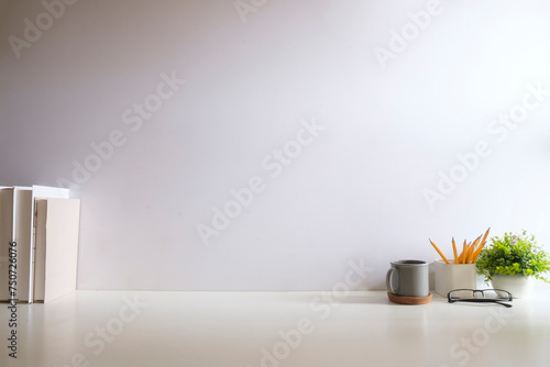 Creative designer workplace with picture frame mock up stationery and potted plant on white table.