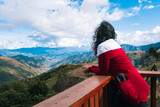 Hermosa mujer usando abrigo rojo posa para con hermoso paisaje de fondo de montañas y cielo azul