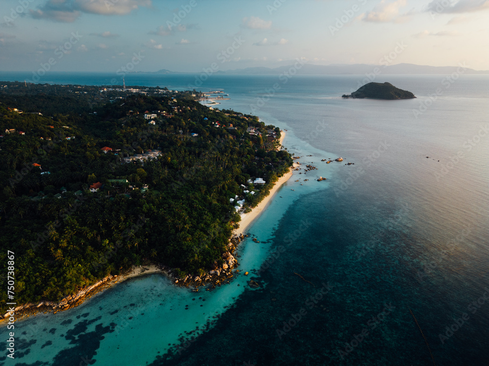 This bird's-eye view reveals a beautiful tropical island. Surrounded by clear turquoise water like glass. The pristine white beaches contrast with the lush greenery of the island's greenery. In the ce This bird's-eye view reveals a beautiful tropical island. Surrounded by clear turquoise water like glass. The pristine white beaches contrast with the lush greenery of the island's greenery. In the ce
