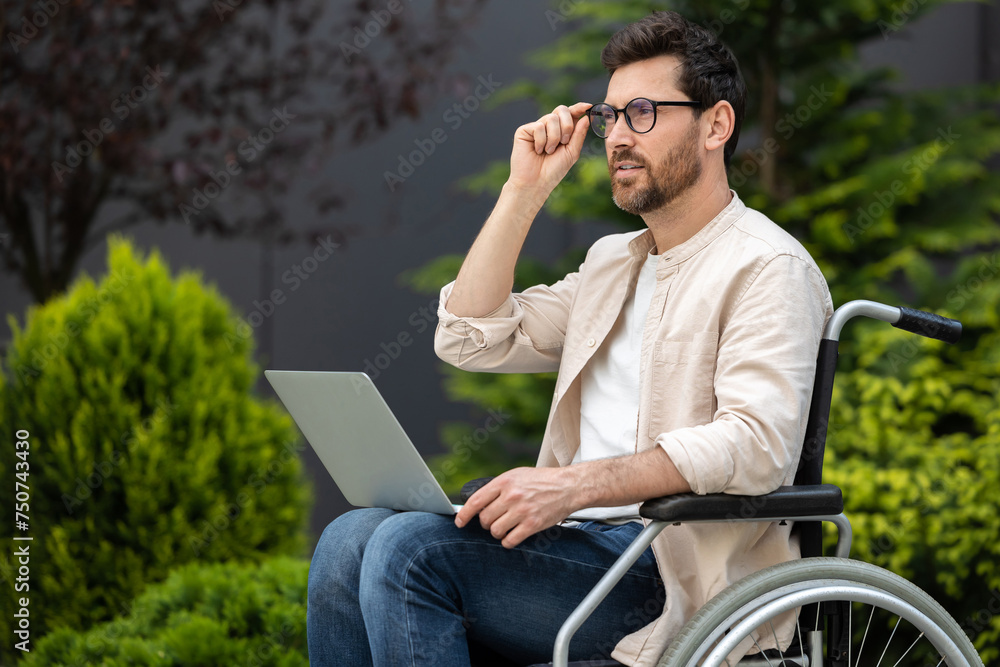 Young bearded man in a wheelchair working on laptop Young bearded man in a wheelchair working on laptop