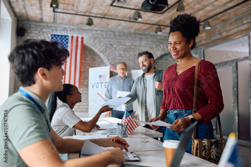 Happy black woman talking to polling place volunteer while signing up for voting during US elections.