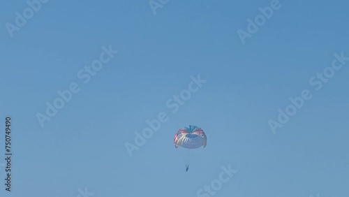 Parasailing above the sea, colourful parachute soaring in clear blue sky photo