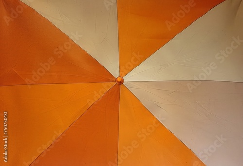 A detailed view of a bright orange and white umbrella, showcasing its vibrant colors and intricate design.