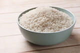 Raw basmati rice in bowl on white wooden table, closeup