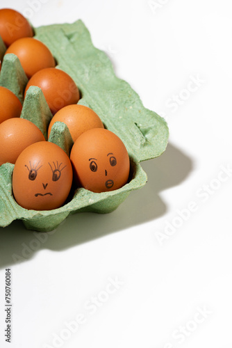 chicken eggs with painted faces on white background, vertical top view