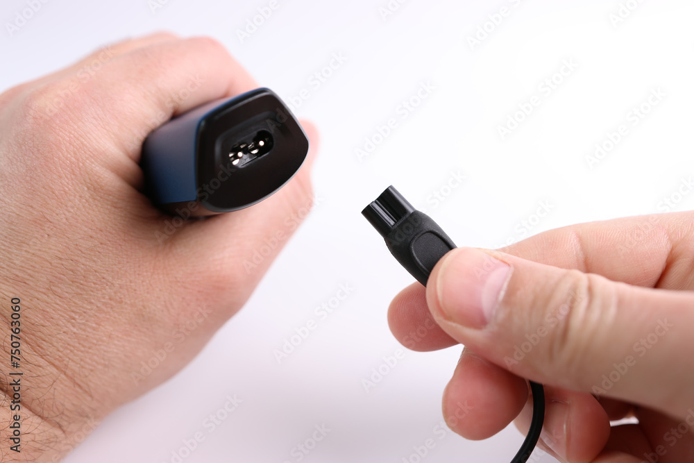The clipper is connected to the power cable. The concept of household electrical appliances. The clipper is connected to the power cable. The concept of household electrical appliances.