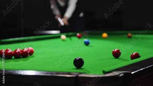 Blurred young man in white shirt playing billiards, snooker game, focusing on shot with cue stick. Concentration and precision. Focus on balls. Billiards sport, gambling, hobby, leisure, game concept photo