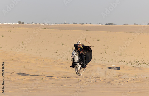 Saudi man in traditional clothing in the deset with a white horse photo