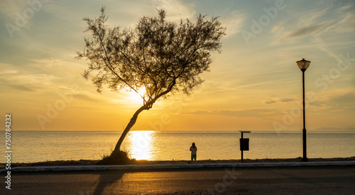 A teenage girl is meditating and exercising on the seashore watching a beautiful sunset. Sithonia, Greece, Halkidiki. Paradisos Beach in Neos Marmaras.
 photo