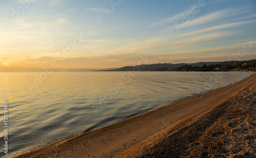 A teenage girl is meditating and exercising on the seashore watching a beautiful sunset. Sithonia  Greece  Halkidiki. Paradisos Beach in Neos Marmaras. 