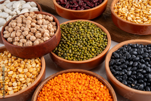 Various dried beans, lentils, mung, chickpea, pea assortment in wooden bowls. Legumes on white table top view. Vegan protein sources food, copy space