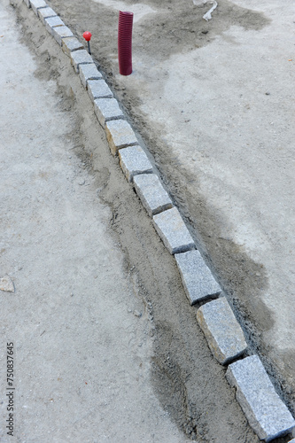 Reform and renewal of the paving of a street with cobblestones. Guide line of granite paving stones for the pavement of a street