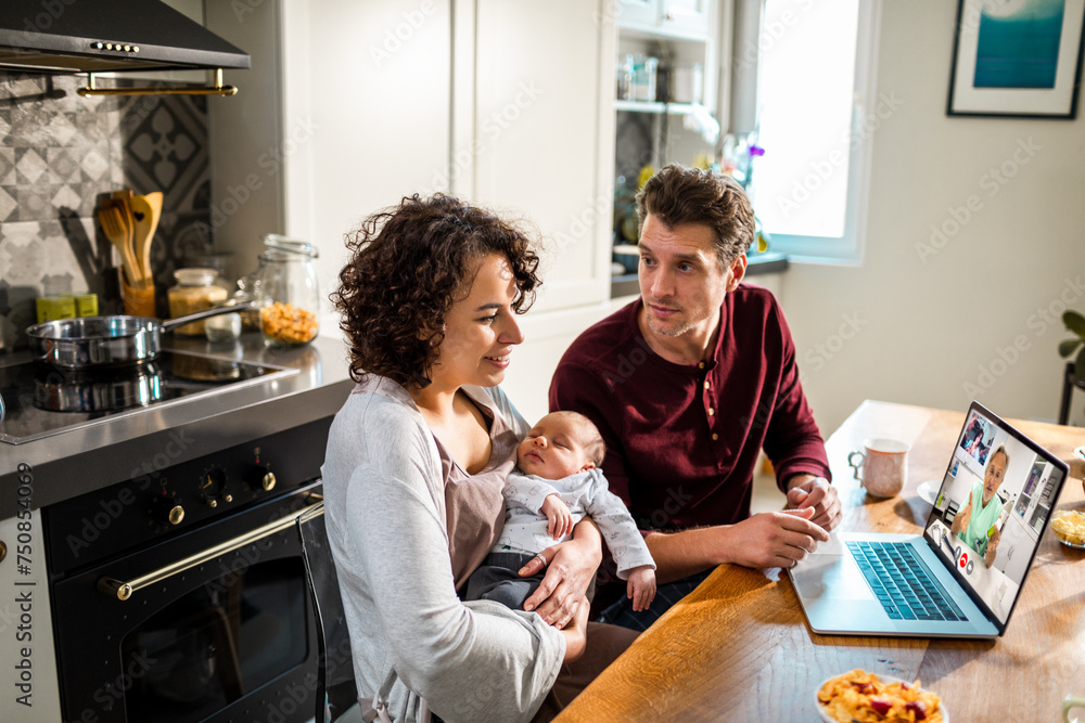 Young couple with baby on video call with doctor at home kitchen Young couple with baby on video call with doctor at home kitchen