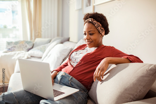 Smiling woman using laptop the couch at home photo