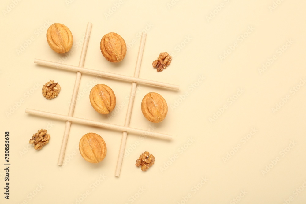 Tic tac toe game made with walnuts and cookies on beige background, top view. Space for text Tic tac toe game made with walnuts and cookies on beige background, top view. Space for text