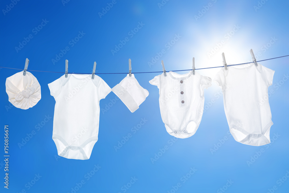 Different baby clothes drying on washing line against blue sky Different baby clothes drying on washing line against blue sky