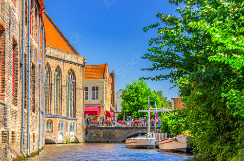 Bakkersrei water canal, Mariabrug bridge and Museum Sint-Janshospitaal building with green trees in Brugge old town quarter district, Bruges city historical centre, West Flanders province, Belgium photo