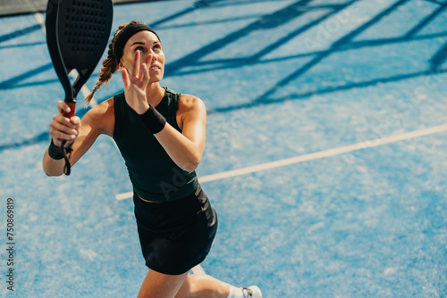 Female athlete receiving a high lob in a padel tennis game photo