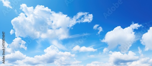 A commercial airplane is seen flying through a bright blue sky with fluffy white clouds on a sunny day. The plane stands out against the clear sky as it soars through the clouds.