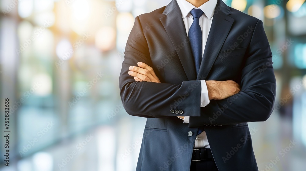Confident Businessman in Suit and Blue Tie, Arms Folded, Office Background Confident Businessman in Suit and Blue Tie, Arms Folded, Office Background