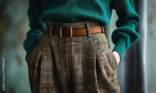 close up of woman's waist with stylish green emerald  sweater and houndstooth pants, brown belt   photo
