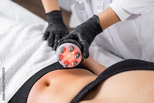 A cosmetologist expertly utilizes RF technology to conduct skin tightening and body contouring procedures to refine the abdominal area of a young woman